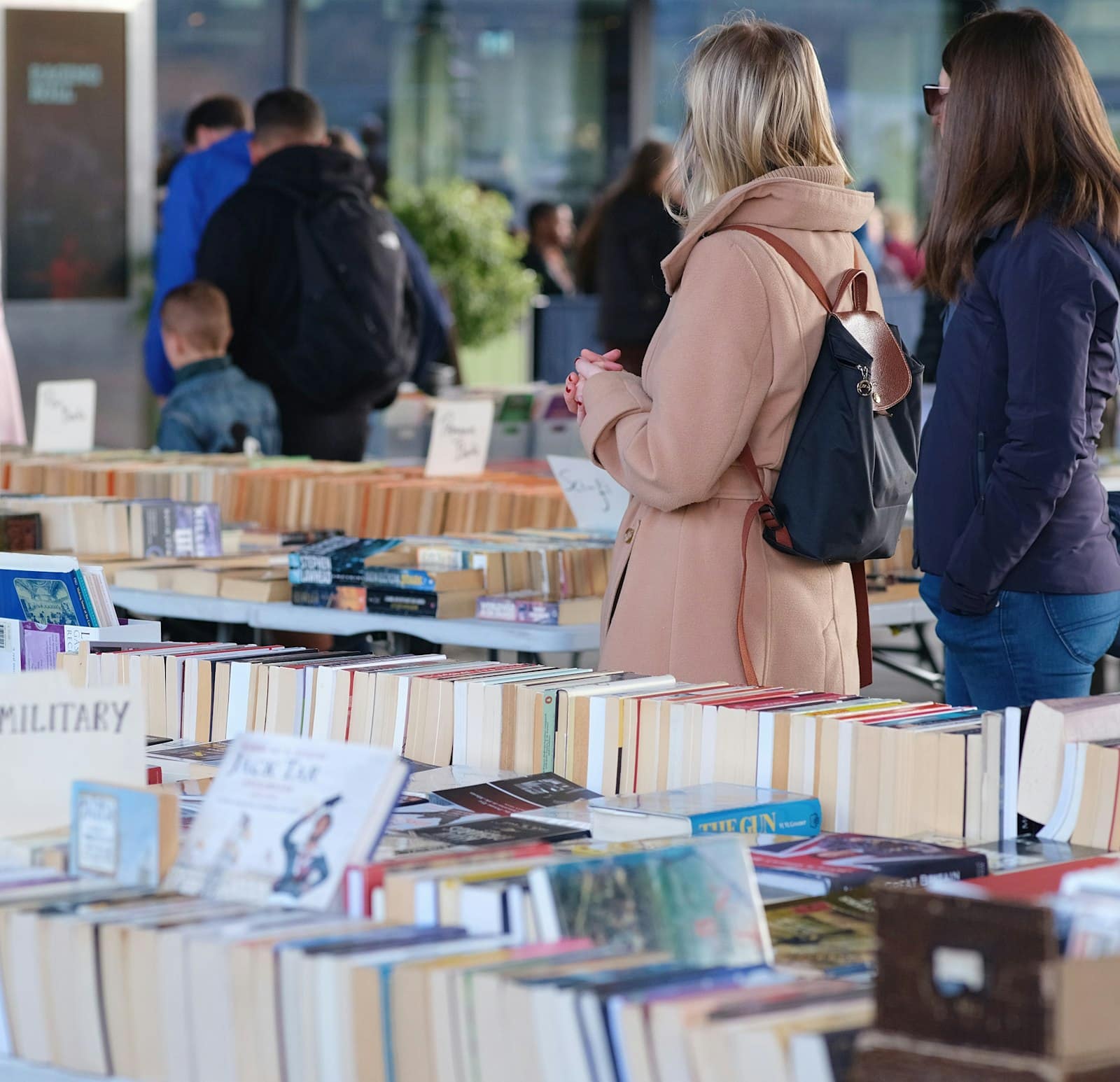 Shoppers browsing long tables of second-hand books at a book fair