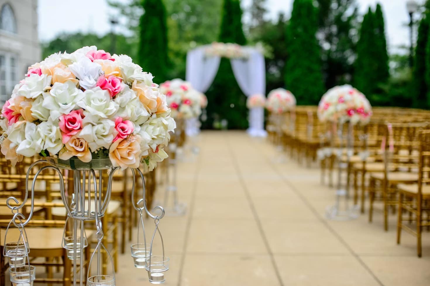 Rose arrangements lining the aisle at an outdoor ceremony